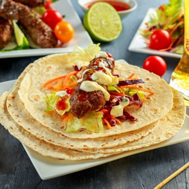Ev yapımı köfte kebap pide, kireç, sebze, bira, beyaz plaka üzerinde tatlı biber ve yoğurt sos ile şiş üzerinde