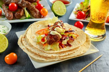 Ev yapımı köfte kebap pide, kireç, sebze, bira, beyaz plaka üzerinde tatlı biber ve yoğurt sos ile şiş üzerinde
