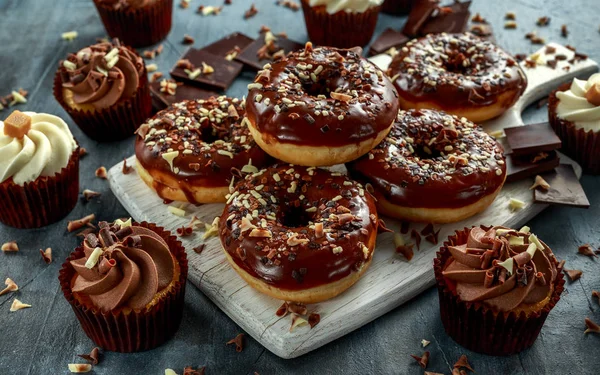 Anéis de donut e cupcakes de caramelo de baunilha com lascas de chocolate branco e escuro e cobertura servida a bordo — Fotografia de Stock