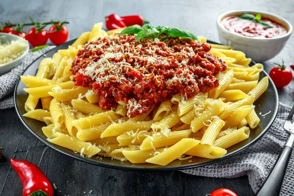 Hete Penne pasta bolognese met Parmezaanse kaas, basilicum, knoflook, tomaten, chili op plaat. — Stockfoto