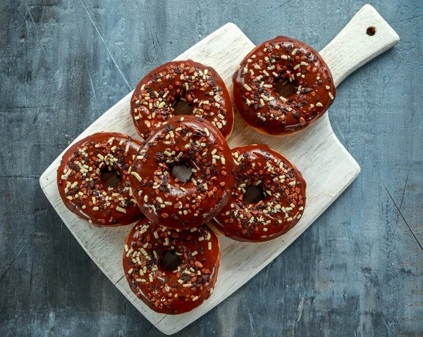 Donut rings with white and dark chocolate chippings and icing served on board — Stock Photo, Image
