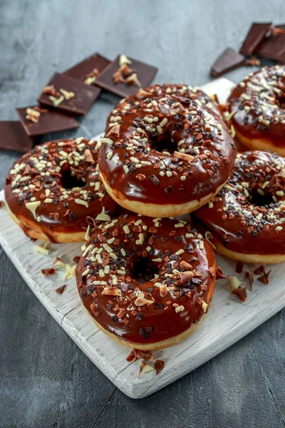 Donut-Ringe mit weißen und dunklen Schokoladenstücken und Zuckerguss an Bord — Stockfoto