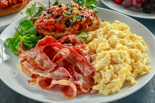 Manhã Ovo mexido, bacon café da manhã com feijão em molho de tomate em pão torrado em prato branco — Fotografia de Stock