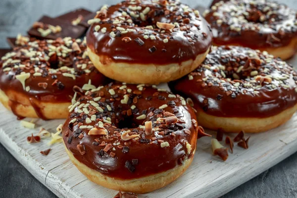 Donut rings with white and dark chocolate chippings and icing served on board — Stock Photo, Image