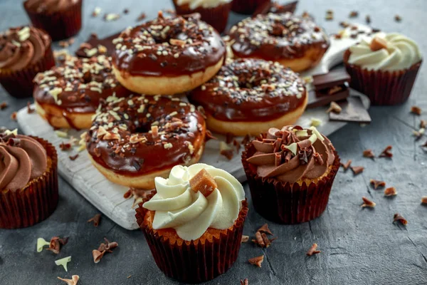 Beignes et cupcakes au caramel à la vanille avec des pépites de chocolat blanc et noir et glaçage servis à bord — Photo