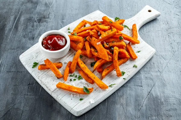 Healthy Homemade Baked Orange Sweet Potato Fries with ketchup, salt, pepper on white wooden board — Stock Photo, Image