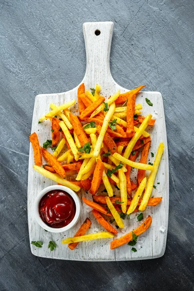 Healthy Homemade Baked Orange Sweet Potato and french Fries with ketchup, salt, pepper on white wooden board — Stock Photo, Image
