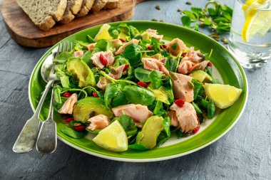 Sağlıklı somon, Avokado salatası su teresi ve goji çilek, yeşil plaka üzerinde kabak çekirdeği mix