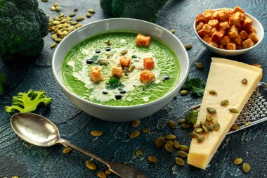 Diyet brokoli yumuşak krem çorbası ile ayçiçeği tohumu, maydanoz yaprakları ve taş masada kruton serpin.