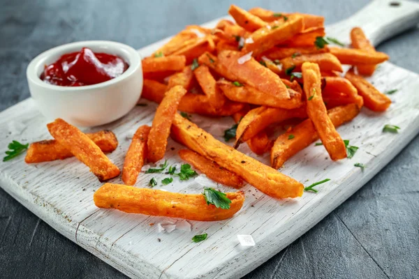 Healthy Homemade Baked Orange Sweet Potato Fries with ketchup, salt, pepper on white wooden board — Stock Photo, Image