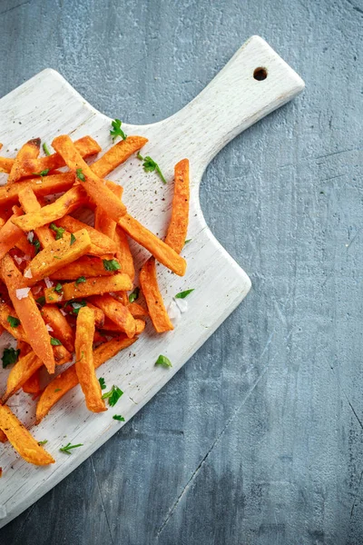 Patatas fritas dulces de naranja horneadas caseras saludables con salsa de tomate, sal, pimienta en un tablero de madera blanco — Foto de Stock