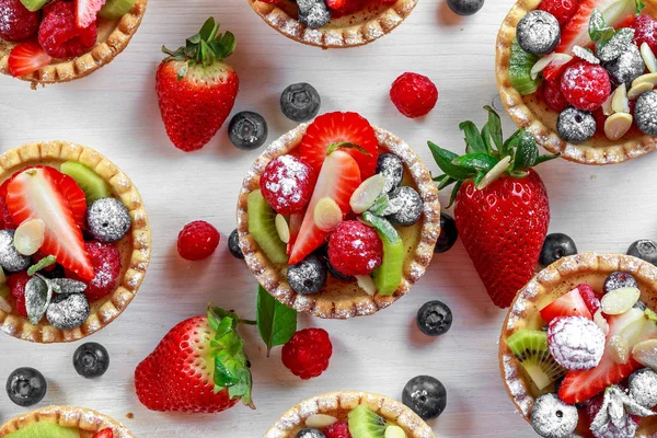 Berry tartlets med blåbär, hallon, kiwi, jordgubbar, mandel flingor i florsocker. — Stockfoto