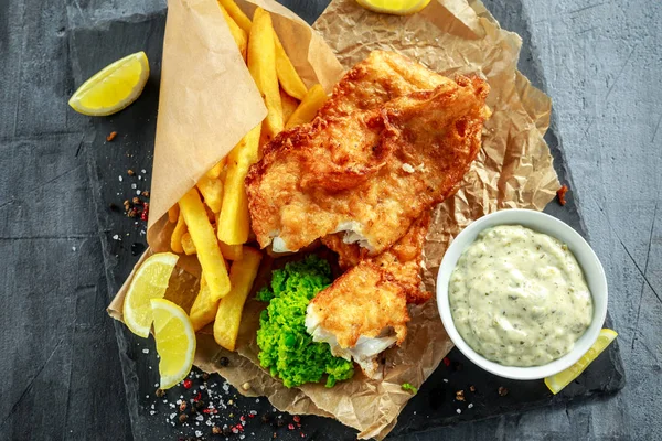 Brittiska traditionella fisk och chips med mosade ärtor, tartarsås på skrynkligt papper. — Stockfoto