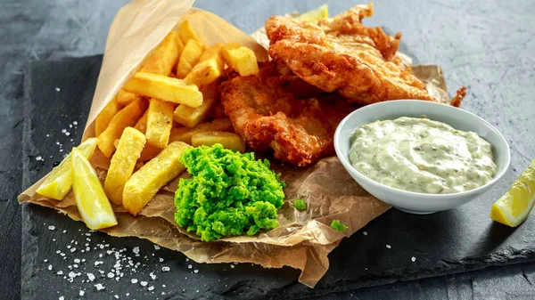 Brittiska traditionella fisk och chips med mosade ärtor, tartarsås på skrynkligt papper. — Stockfoto