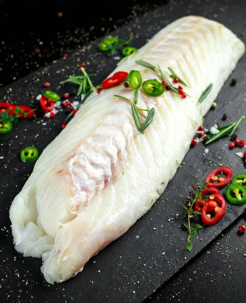 Fresh Raw Cod loin fillet with rosemary, chillies, cracked pepper and lemon on stone board — Stock Photo, Image