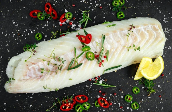 Färsk rå fläskkarré torskfilé med rosmarin, chili, spruckna peppar och citron sten ombord — Stockfoto