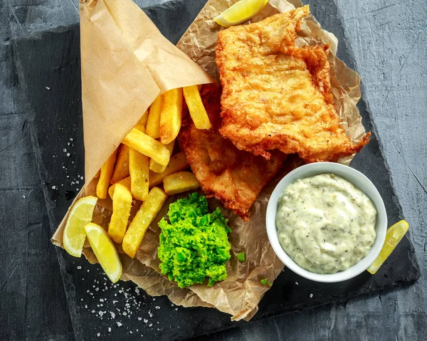 イギリスの伝統的な魚とマッシュ豆チップ、しわくちゃの紙にタルタル ソース. — ストック写真