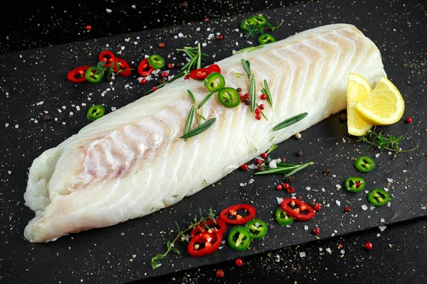 新鲜原料里脊肉银鳕鱼迷迭香、 红辣椒、 黑椒柠檬石材板上 — 图库照片