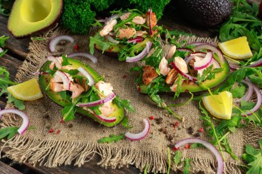 Avokado tekneler somon, kırmızı soğan ve roka ile doldurulmuş. kavram sağlıklı gıda