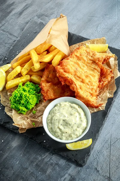 Brittiska traditionella fisk och chips med mosade ärtor, tartarsås på skrynkligt papper. — Stockfoto