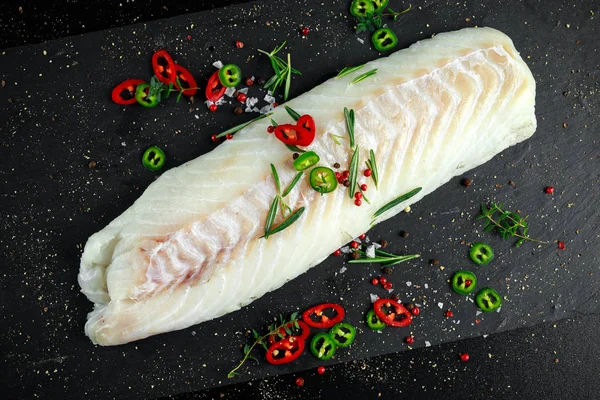 Fresh Raw Cod loin fillet with rosemary, chillies, cracked pepper on stone board — Stock Photo, Image