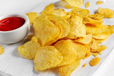 Altın ve beyaz tahta üzerinde sıcak soslu çıtır patates cipsi arka plan.