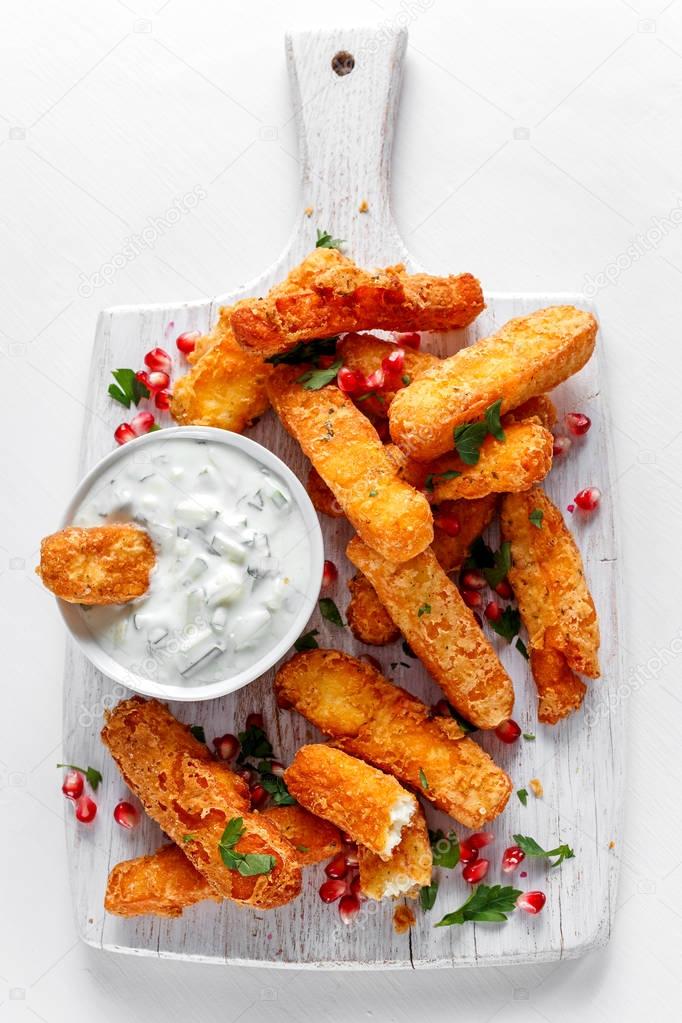 Crispy Halloumi cheese sticks Fries with yogurt for dipping and pomegranate seeds.