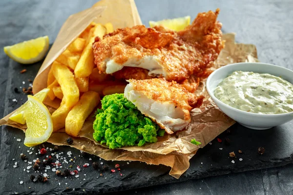 イギリスの伝統的な魚とマッシュ豆チップ、しわくちゃの紙にタルタル ソース. — ストック写真