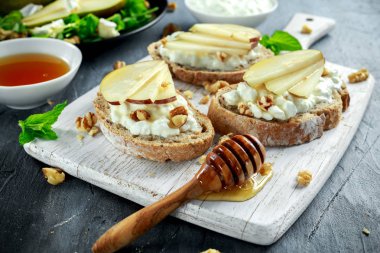 Taze tatlı armut salatası ve süzme peynir ile bruschetta, ceviz beyaz tahta üzerinde.