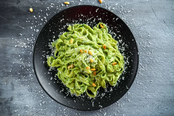 Siyah plaka üzerinde Tagliatelle makarna pesto sos, çam fıstığı ve parmesan ile.