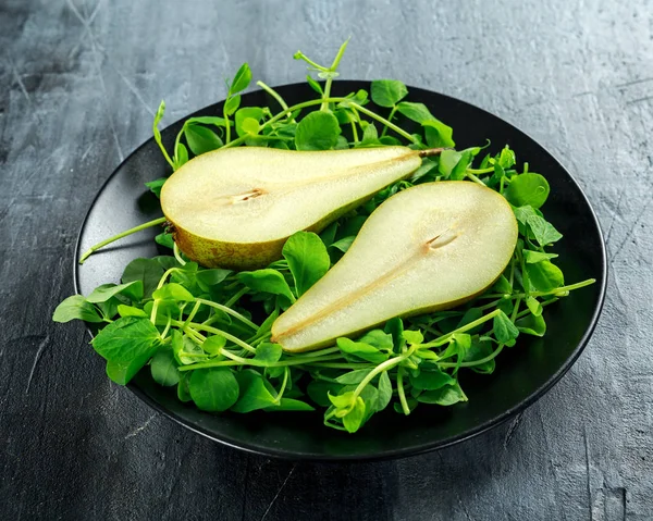 Pêras doces frescas com salada verde na placa preta — Fotografia de Stock
