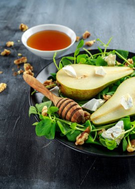Ceviz, bal ve siyah plaka üzerinde beyaz peynir ile taze tatlı armut salatası