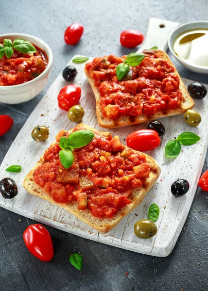Färsk hemmagjord krispig italiensk förrätt Bruschetta toppad med tomat, aubergine, Zucchini, gul paprika, vitlök och basilika på vit träskiva. hälsosam mat — Stockfoto