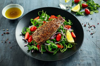 Domates, füme uskumru salatası doğranmış kırmızı soğan, Ruccola siyah plaka üzerinde.