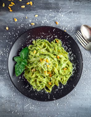 Siyah plaka üzerinde Tagliatelle makarna pesto sos, çam fıstığı ve parmesan ile.