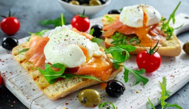 Somon füme, rucola, zeytin ve beyaz tahta üzerinde sebze ızgara ekmek üzerine haşlanmış yumurta. sağlıklı kahvaltı