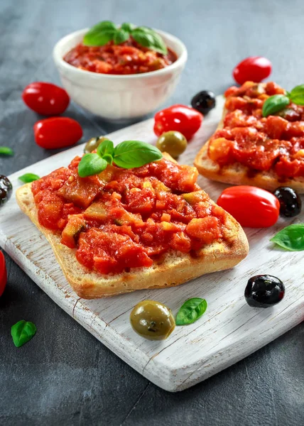 Färsk hemmagjord krispig italiensk förrätt Bruschetta toppad med tomat, aubergine, Zucchini, gul paprika, vitlök och basilika på vit träskiva. hälsosam mat — Stockfoto