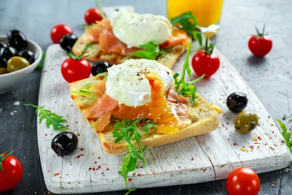 Somon füme, rucola, zeytin, sebze ve portakal suyu ile ızgara ekmek üzerine haşlanmış yumurta. Beyaz tahta üzerinde. sağlıklı kahvaltı