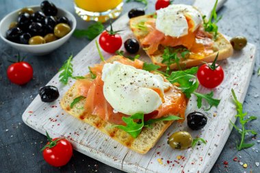 Somon füme, rucola, zeytin, sebze ve portakal suyu ile ızgara ekmek üzerine haşlanmış yumurta. Beyaz tahta üzerinde. sağlıklı kahvaltı