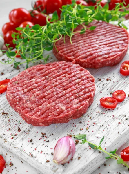 Carne fresca cruda, empanadas redondas para hacer hamburguesa casera en tablero blanco de madera — Foto de Stock