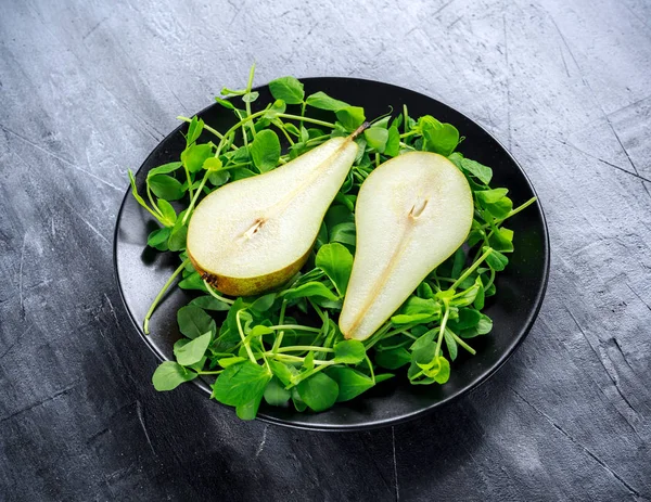 Siyah plaka üzerinde yeşil salata ile taze tatlı armut — Stok fotoğraf
