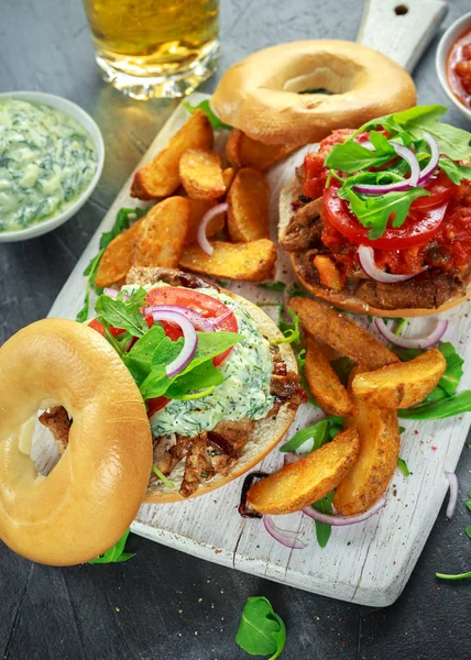 Deliciosos sanduíches de porco Bagel com molho vegetal e Tzatziki e batatas fritas na tábua branca . — Fotografia de Stock