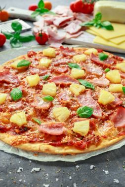 Taze pişmiş pizza hawaii ile jambon ve ananas, fesleğen, domates yedeklenmiş kağıt üzerinde