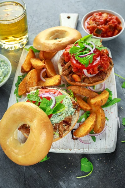 Deliciosos sanduíches de porco Bagel com molho vegetal e Tzatziki e batatas fritas na tábua branca . — Fotografia de Stock