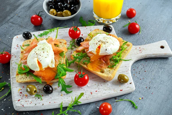 Somon füme, rucola, zeytin, sebze ve portakal suyu ile ızgara ekmek üzerine haşlanmış yumurta. Beyaz tahta üzerinde. sağlıklı kahvaltı