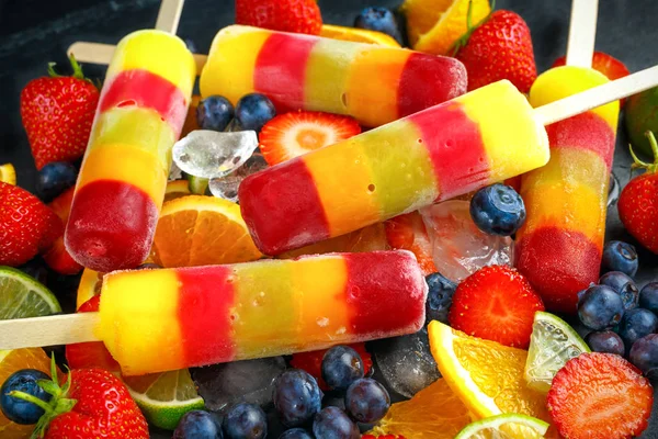 Healthy refreshing fruit popsicle lollies with orange, lime, strawberries, blueberries. — Stock Photo, Image