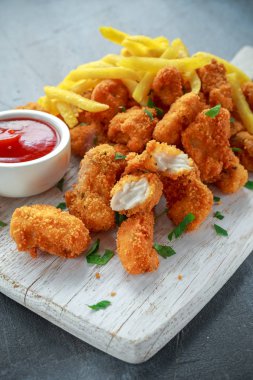 Kızarmış tavuk nugget, yanında patates kızartması ve ketçap.