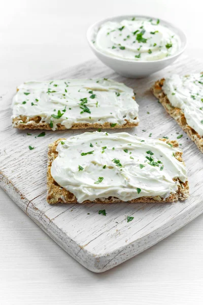 Tostadas caseras de pan crujiente con queso crema y perejil sobre fondo de tabla de madera blanca . —  Fotos de Stock