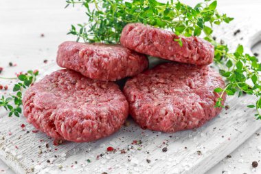 Eve el yapımı çiğ kıyılmış sığır eti biftek hamburger ahşap tahta üzerinde.