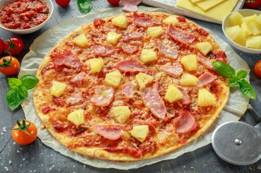 Taze pişmiş pizza hawaii ile jambon ve ananas, fesleğen, domates yedeklenmiş kağıt üzerinde